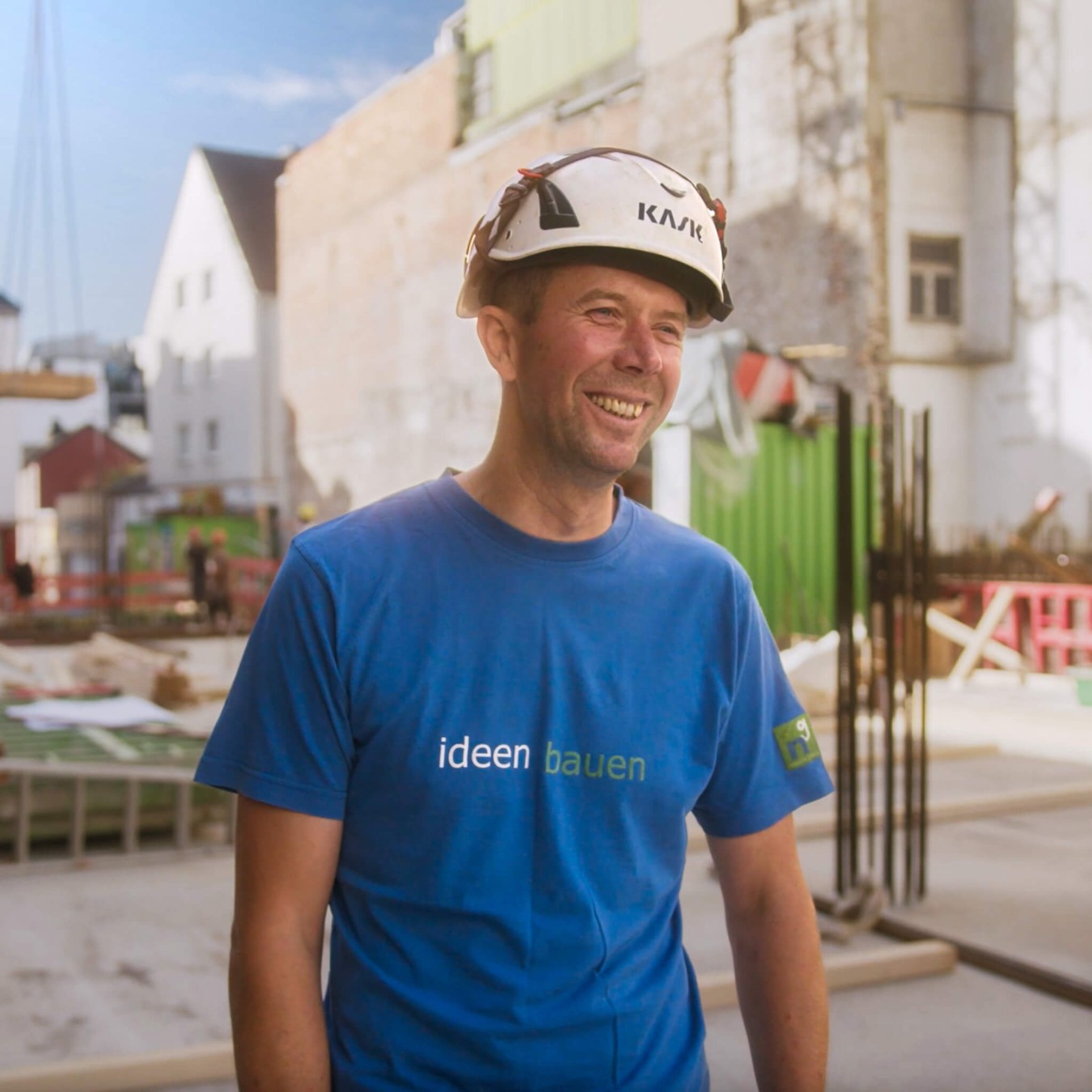 Ein Polier mit Helm steht auf einer sonnigen Baustelle und berichtet über specter automation, eine Baumanagement Software.
